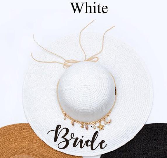 White beach floppy hat with bride written in black and shell charms. 